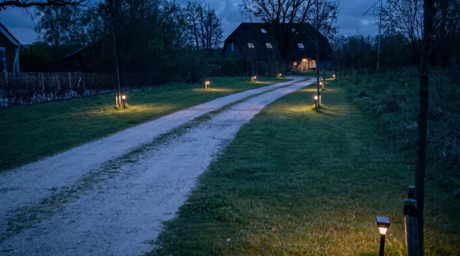 Wegebeleuchtung entlang einer langen Einfahrt zeigt den Weg zum Haus und erhoeht die Sicherheit nachts
