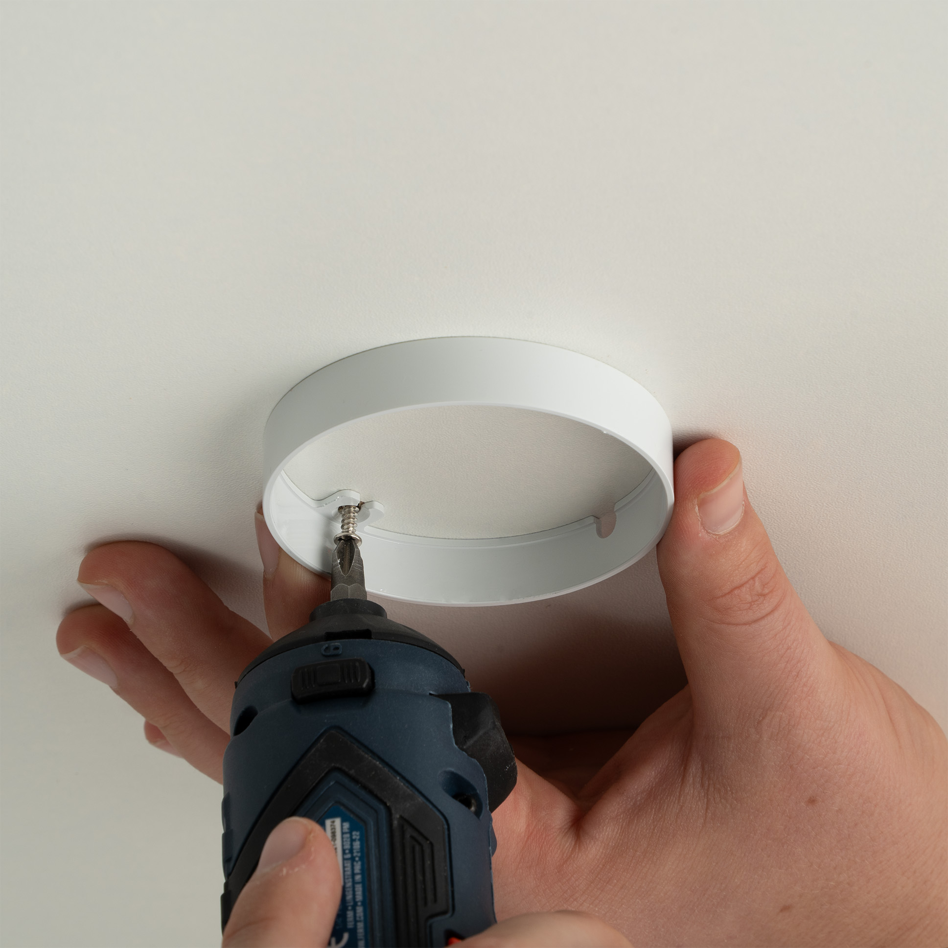 Gehaeuse einer LED Einbauleuchte wird mit Schrauben an der Decke befestigt