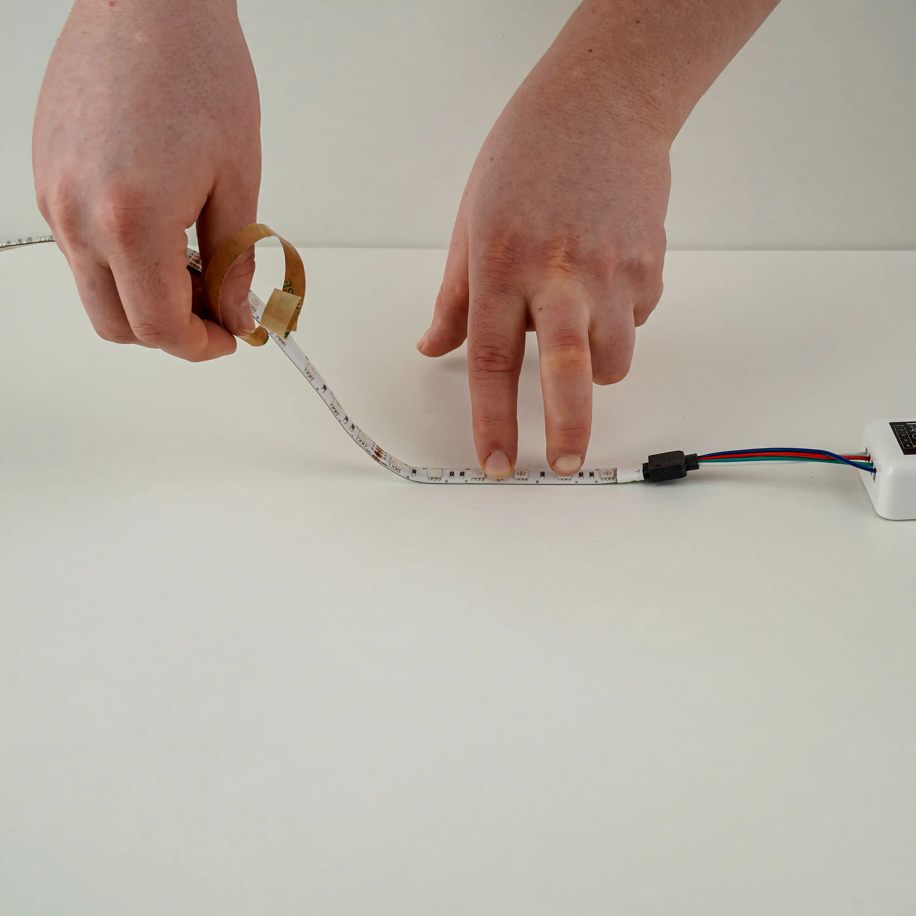 LED-Streifen montieren indem die Schutzfolie der Klebeschicht entfernt wird fuer einfache Befestigung