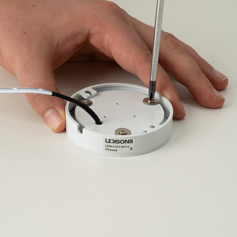 Montageplatte einer LED Aufbauleuchte mit Schraubendreher loesen fuer Montage oder Wartung