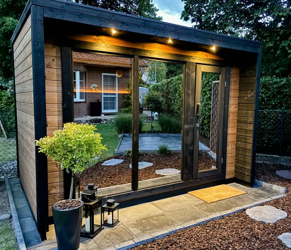 Aussensauna mit mehreren LED Spots unter dem Dach die den Eingangsbereich warm beleuchten